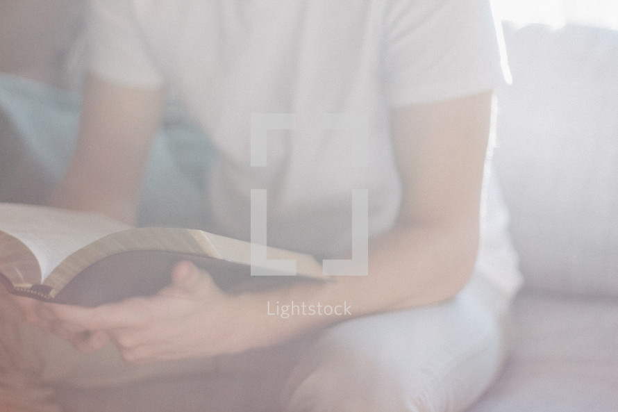 torso of a teen boy reading a Bible 