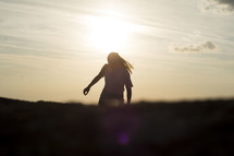 silhouette of a woman walking at sunset 