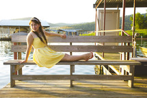 teen girl in a yellow sundress sitting on a bench 