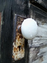 Though I stand at the door and knock - a large metal door knob against a grainy wooden door. 