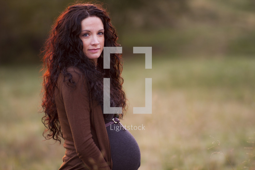 Pregnant woman standing in a field.