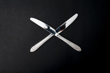 two butter knives on a black background 