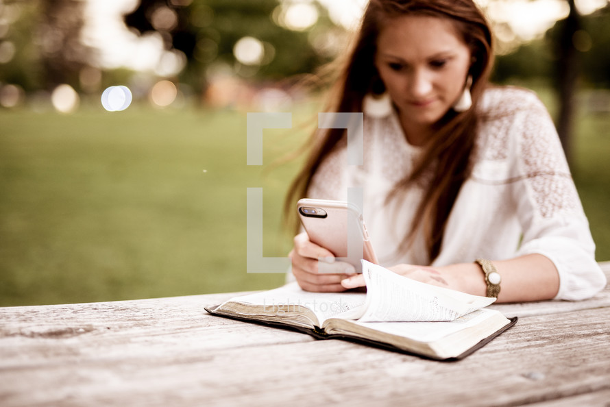 woman reading a Bible and using a cellphone 