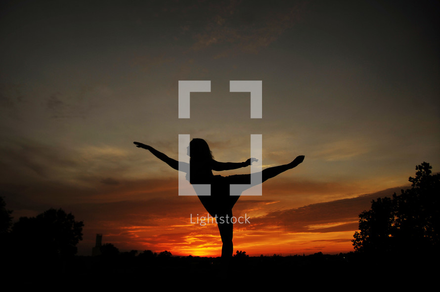 girl in ballet poise against sunset