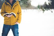 a man walking in snow carrying a Bible 