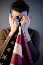 A man crying into an American flag 