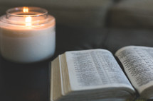 open Bible and candle on an ottoman