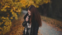 a brunette in a scarf standing outdoors in fall 