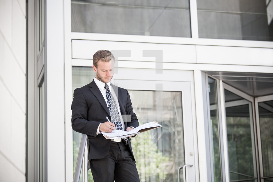 businessman writing in a notebook outdoors 
