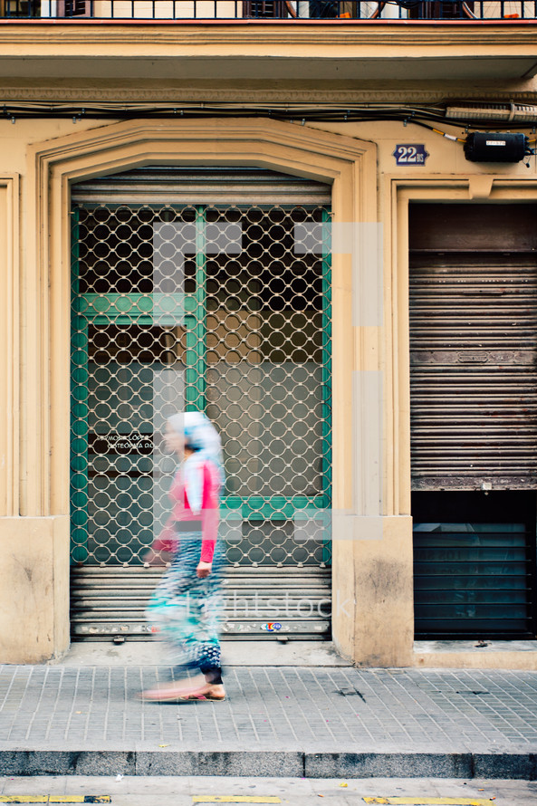 a woman walking on a sidewalk in Barcelona 