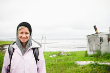 woman wearing a hoodie and cap standing near a coastal shore