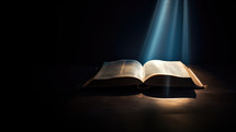 Open bible with glowing beam of light on dark background. Selective focus
