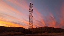 Colorful sunset clouds beyond a communications tower