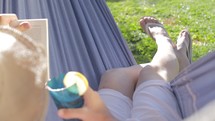 enjoying a glass of lemonade in a hammock reading a book 