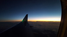 Window seat view of an airline wing at dusk