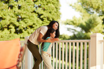 a woman standing on a back porch with her daughter 