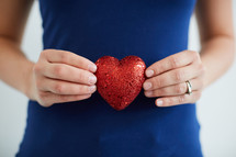 a woman holding a red heart in her hands 