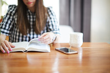 a woman sitting at a desk reading a Bible 
