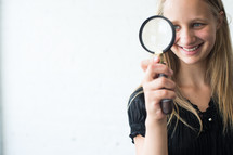 teen girl looking through a magnifying glass 
