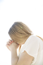 a young woman with head bowed in prayer. 