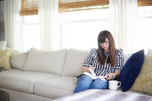 a woman sitting on a couch a Bible at home 