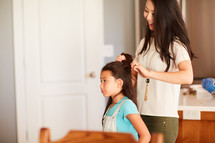 a mother doing her daughter's hair 
