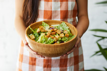 a woman holding a bowl of salad 