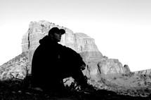 silhouette of man sitting in front of a mountain peak 
