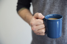 A man holding a blue cup full of coffee.