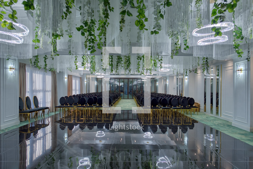 Chairs set up for wedding with greenery hanging from ceiling