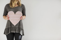 a woman holding a wooden heart