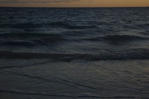 waves washing onto a beach at dusk 
