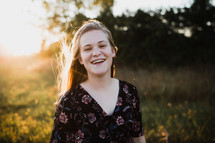 smiling woman in a field at sunset 