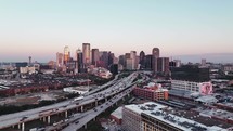 Aerial video of downtown Dallas, Texas during sunrise with highways, traffic and skyscraper buildings in the background.