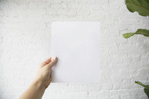 a man holding up a blank piece of white paper 