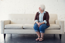 an elderly woman sitting on a couch 