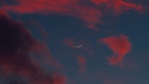 Segment of new moon with red clouds 