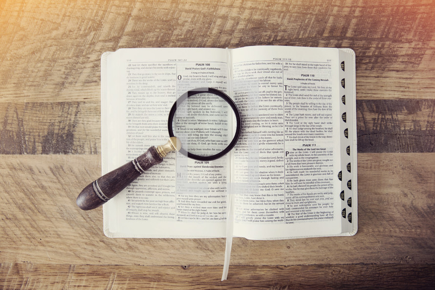 a magnifying glass over the pages of a Bible 