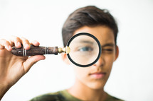 boy child looking through a magnifying glass 