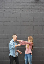 a couple hugging in front of a gray wall 