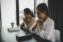 Two Asian women praying to god together in church.