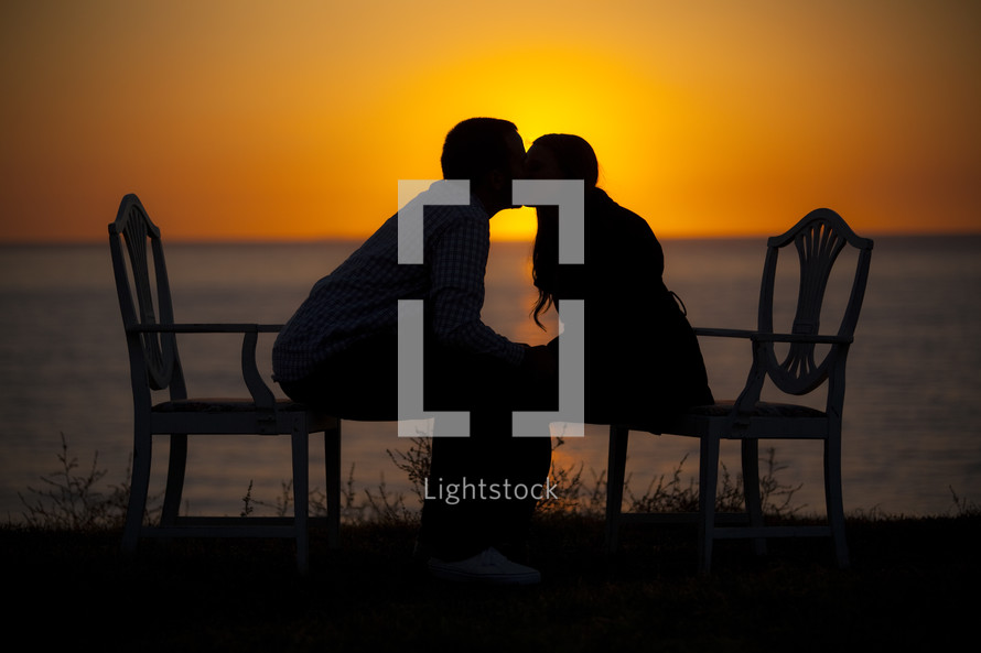 Silhouettes of a man and woman kissing at sunset