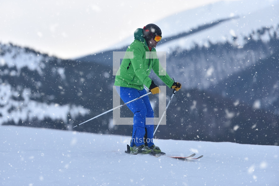 A novice adult skier carefully descends the snowy slopes during a snowfall