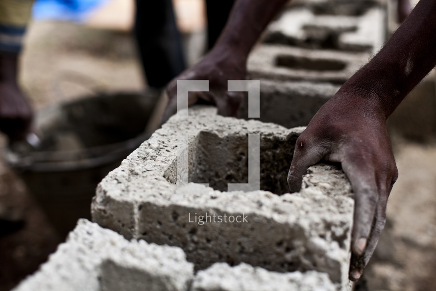 A man uses cinder block to build a wall on a new church