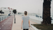 woman walking along a harbor 