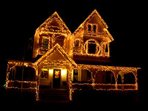 A Christmas Ginger bread house decorated with Christmas lights adorns the night sky at Christmas time. 