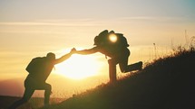 Silhouette two people working in team mountain rock climbing. Helping hand friend to overcome difficulties. Dangerous sport in nature. Business partner. Tourists with backpack and hiking accessories.