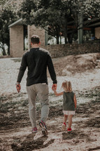 father and daughter walking holding hands outdoors 