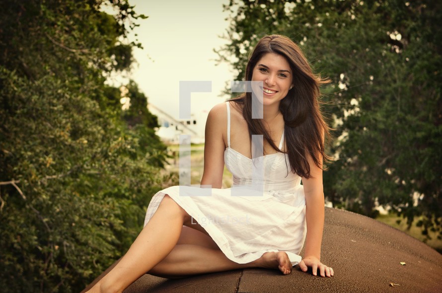 teen in a white dress siting outside