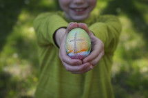smiling boy holding an Easter egg with cross
